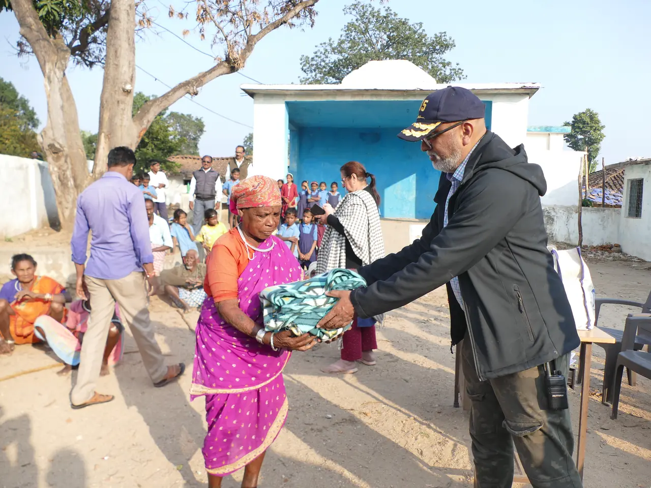 An OAI member handing a warm blanket to a village resident during a winter distribution drive