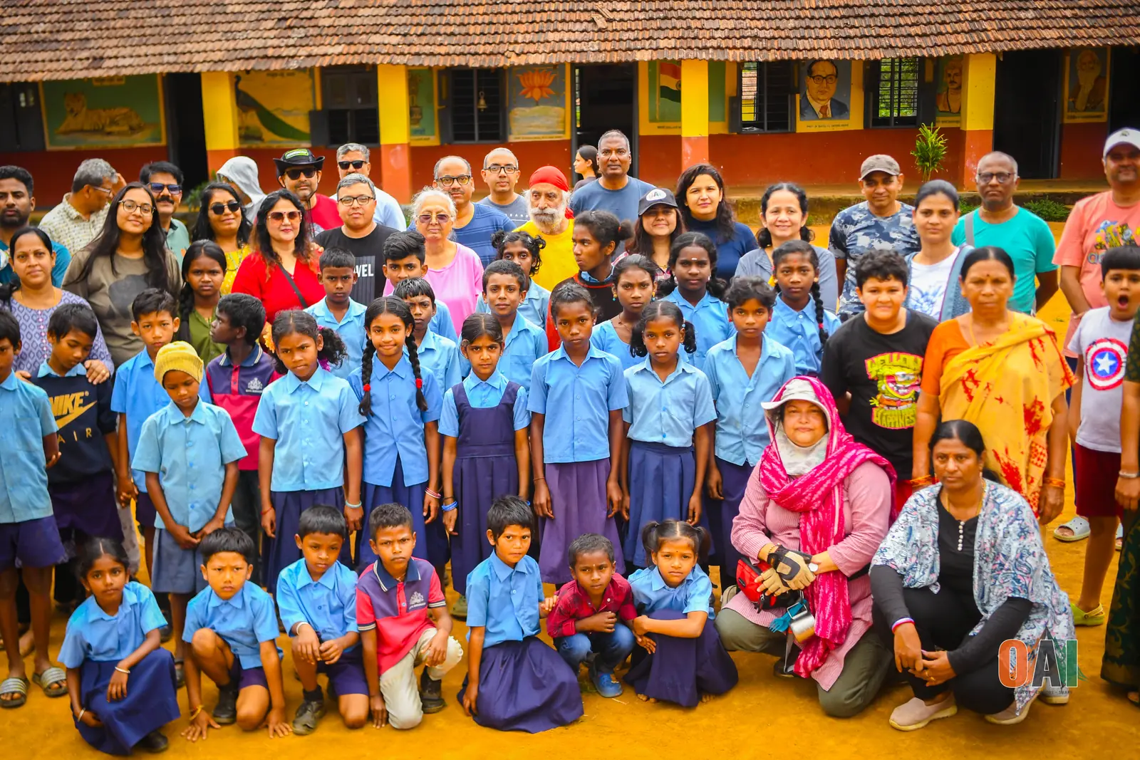 OAI members and schoolchildren posing together outside a rural school