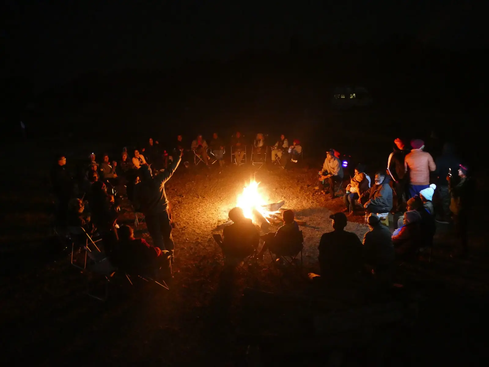 OAI members gathered around a campfire at night during a Sangam meet