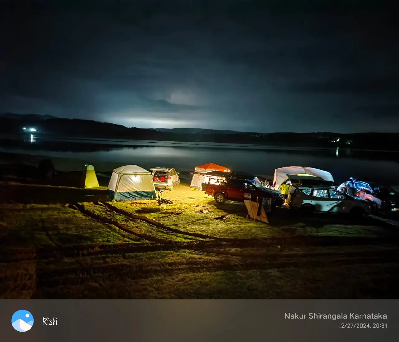 OAI vehicles and tents illuminated at night beside a lake
