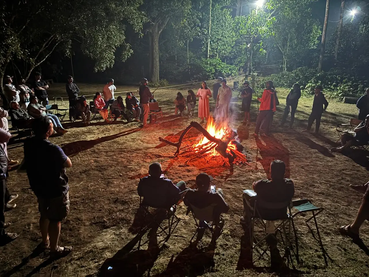 OAI members gathered in a circle around the bonfire, Theralu Village