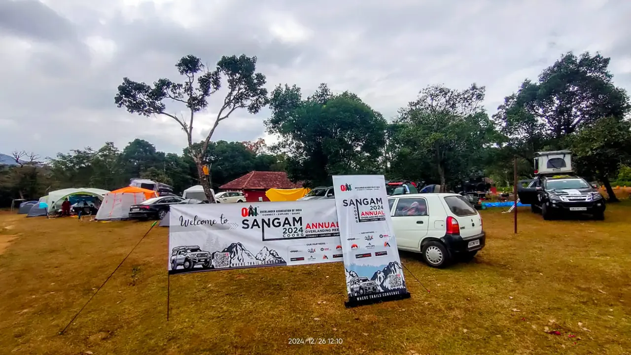 Welcome to Sangam 2024 Coorg banner with vehicles and tents at the Theralu Village campsite